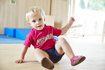 Ein kleiner Bub sitzt am Boden.